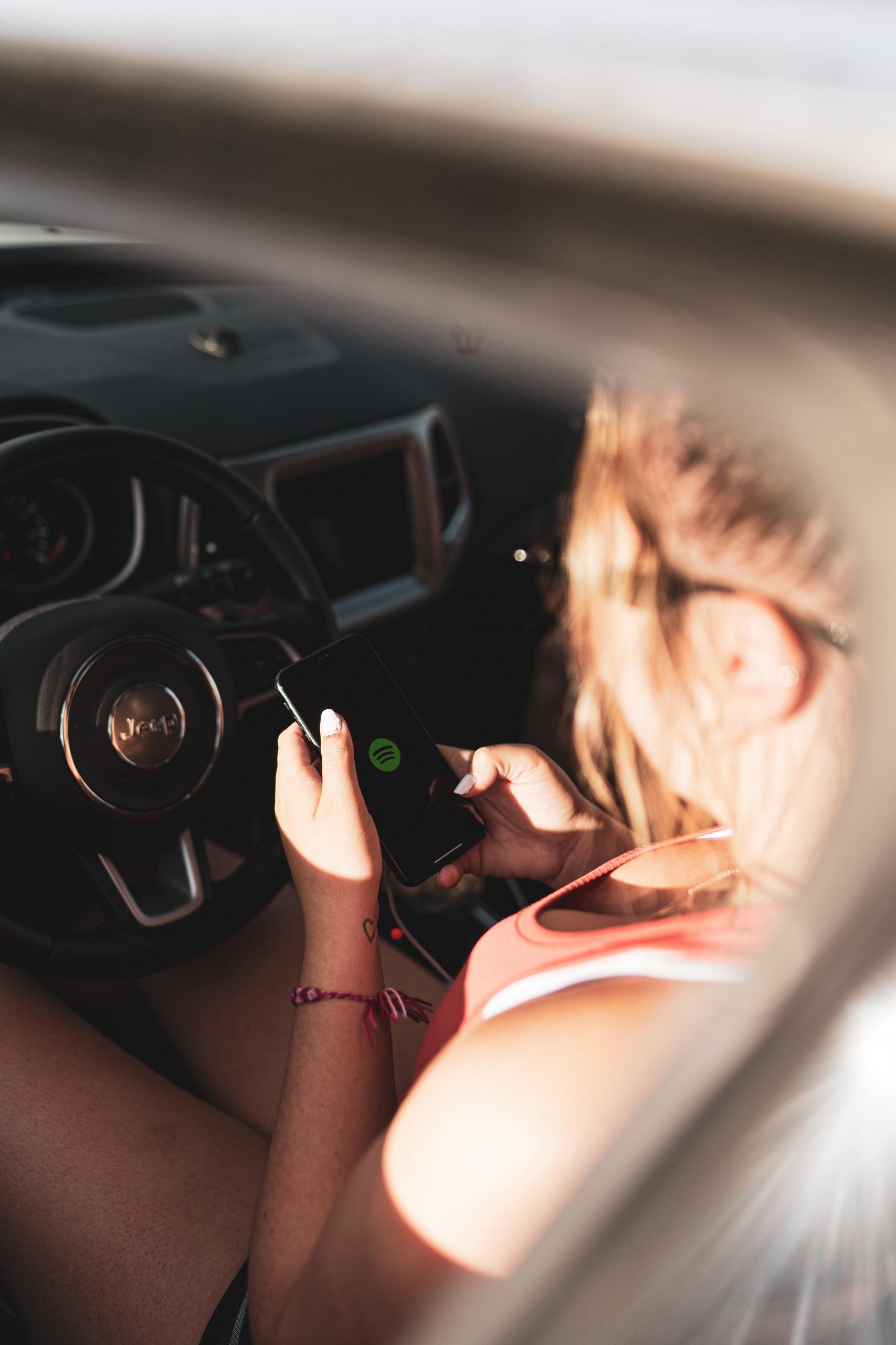Une femme allume Spotify dans sa voiture pour écouter de la musique.