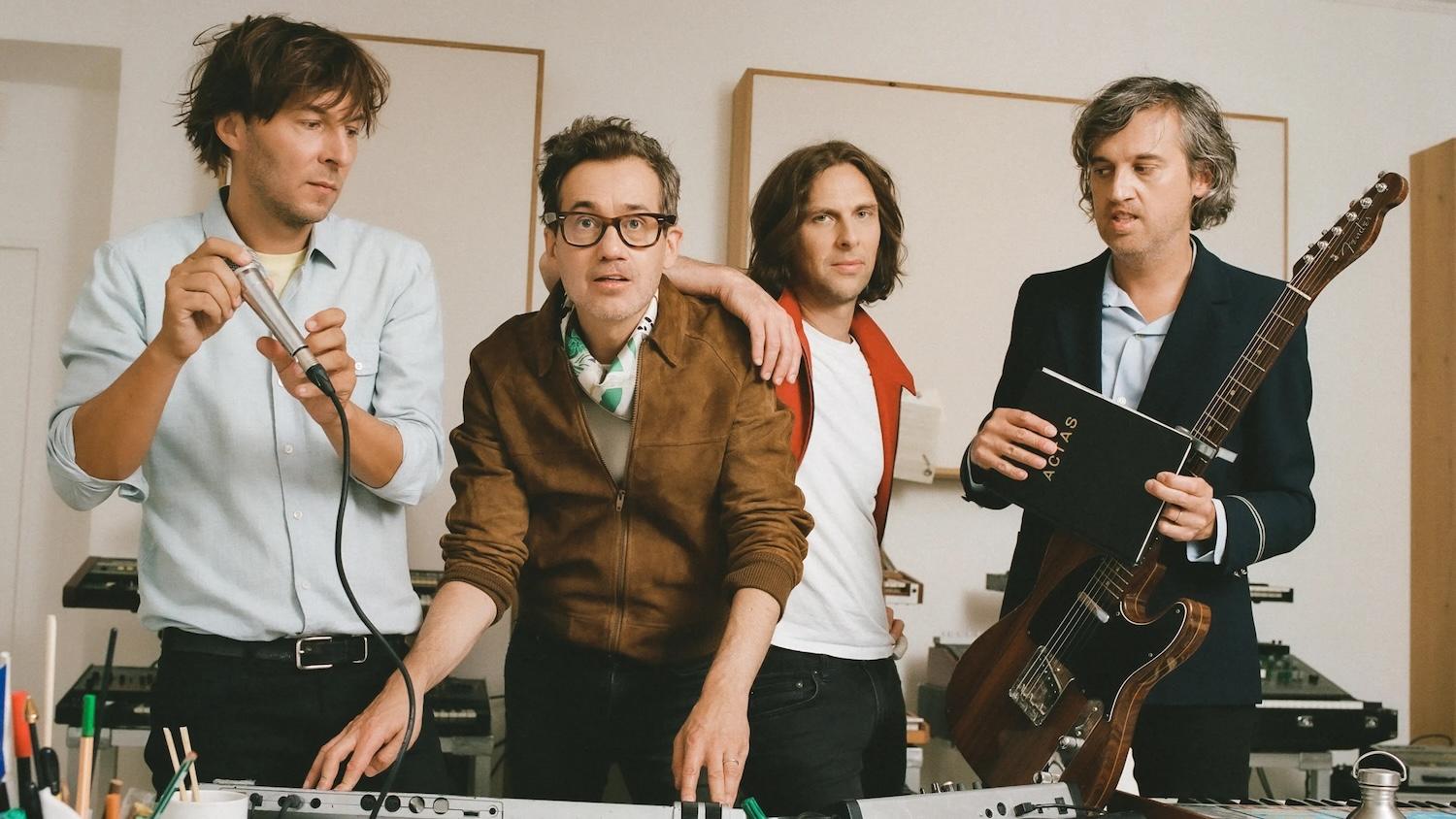 Les 4 membres du groupe Phoenix sont les uns à côté des autres dans une salle de musique.