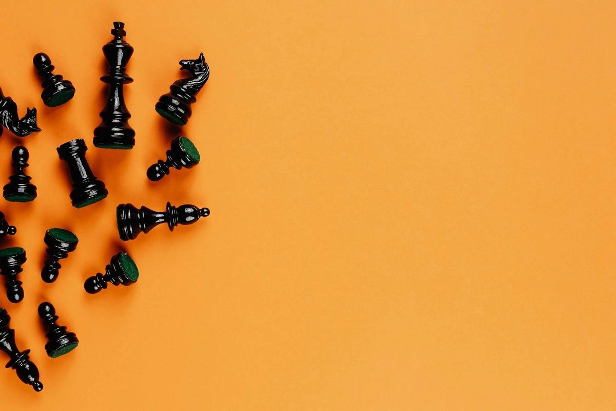 Des pions d'échecs sont renversé sur un fond orange.