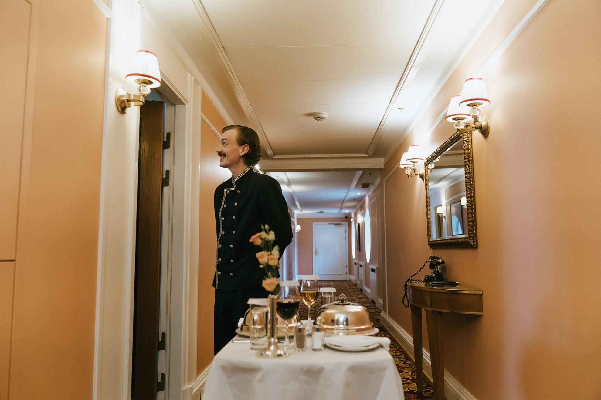 Un employé d'hôtel servant un client en room service.