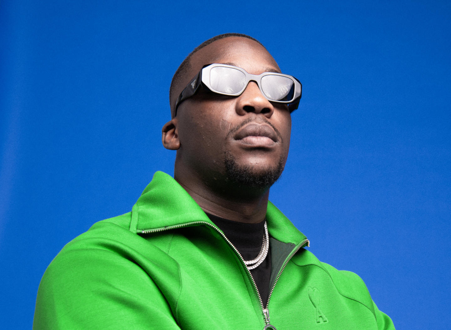 Le rappeur SDM sur fond bleu avec des lunettes de soleil.
