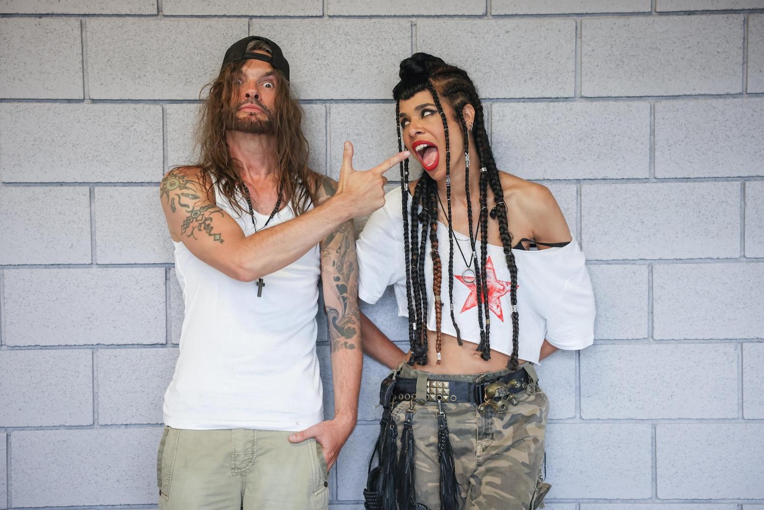 Les 2 membres de Shaka Ponk sont le long d'un mur en briques grises.