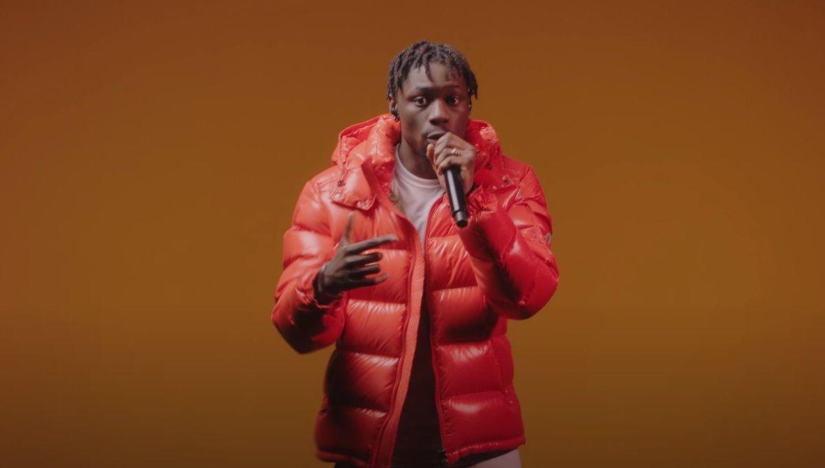 Le rappeur Tiakola chante avec une doudoune rouge.