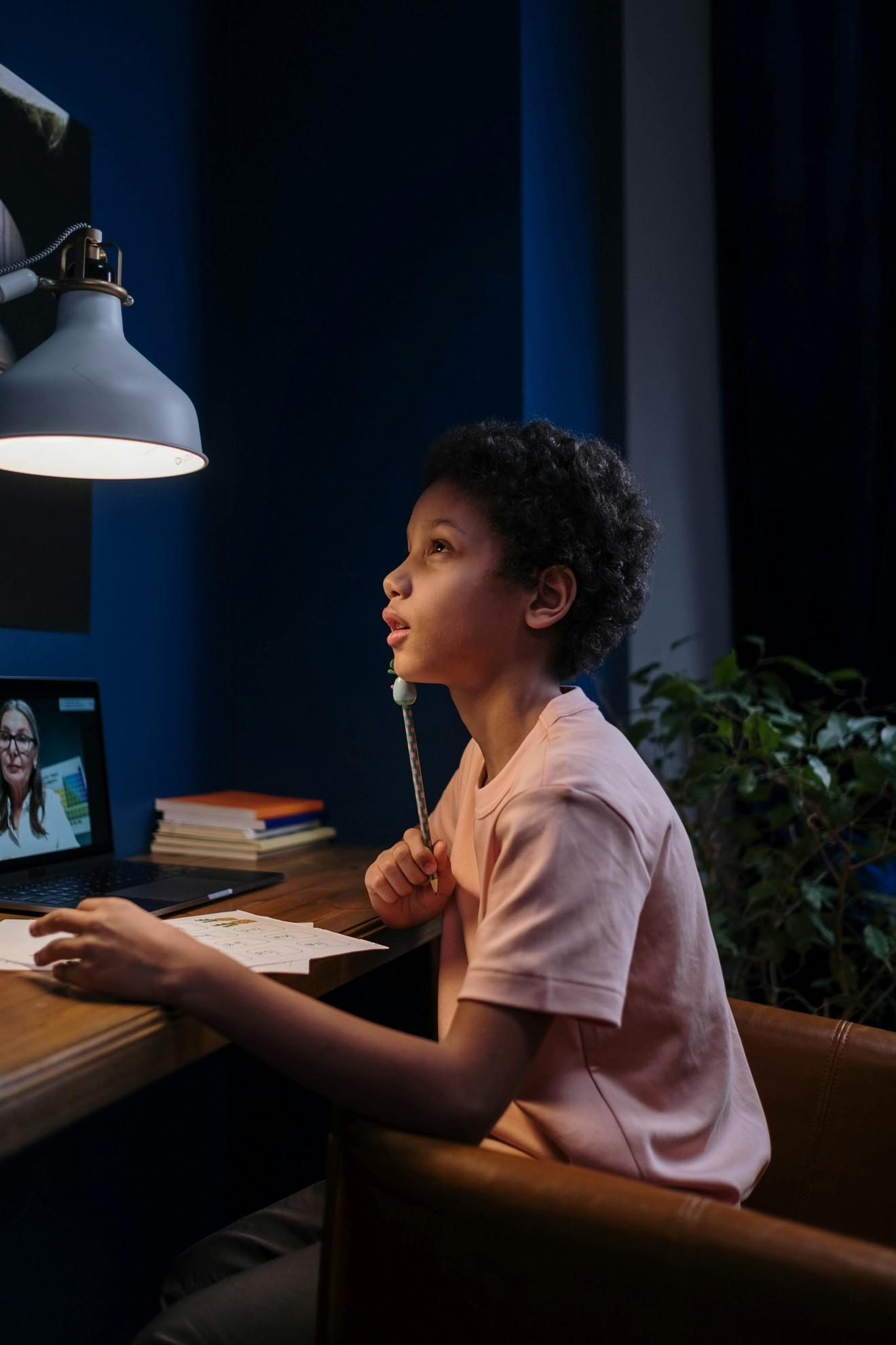Un jeune élève en train de réfléchir devant ses devoirs.