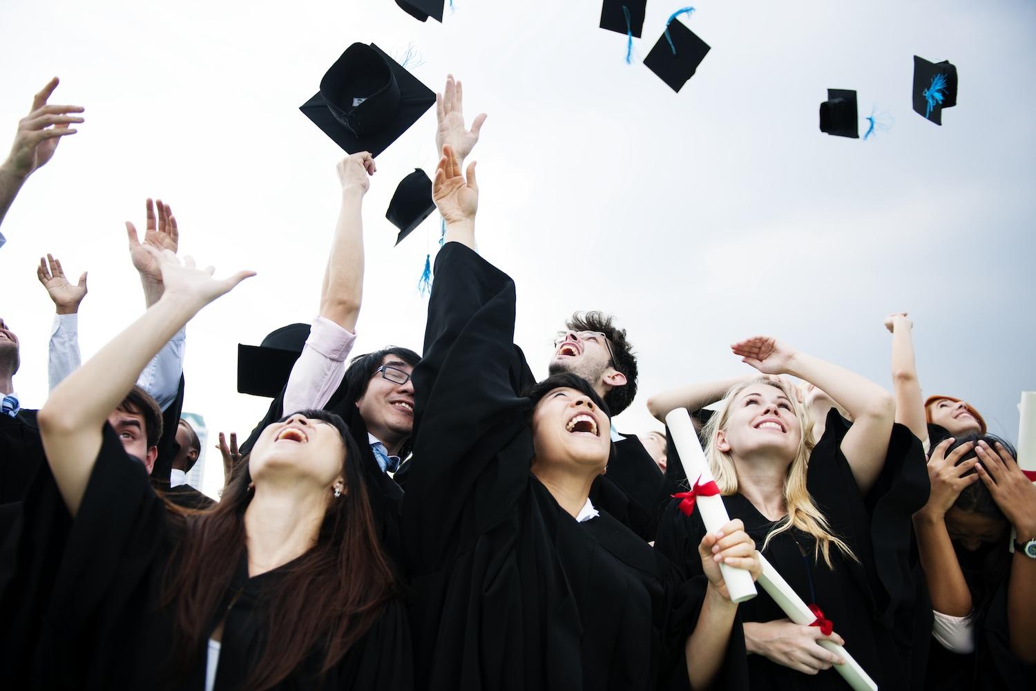 Plusieurs étudiants lancent leur chapeau en l'air.