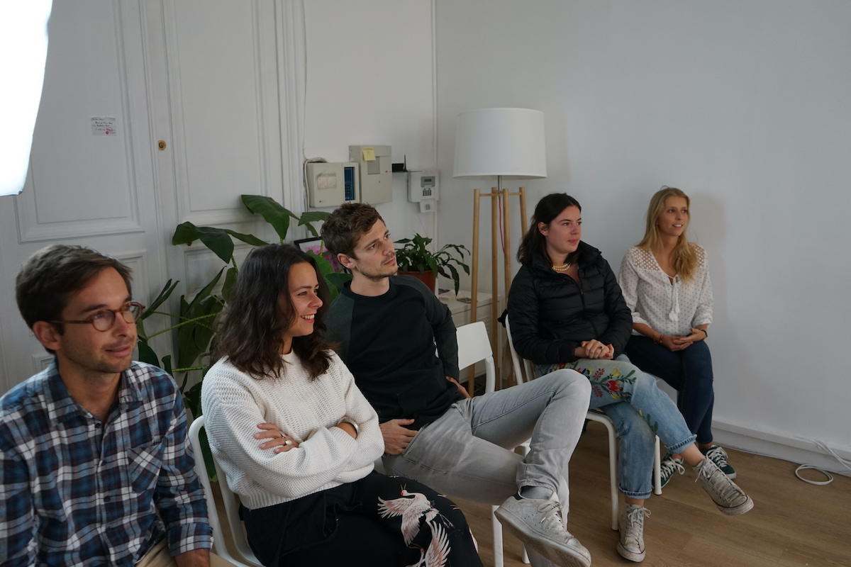 5 personnes assises sur des chaises et écoutant les conseils d'un professeur de théâtre. 