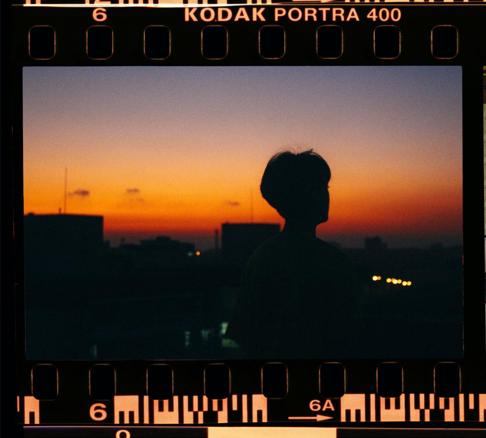 Une bobine de photo film montre une personne devant un coucher de soleil. 