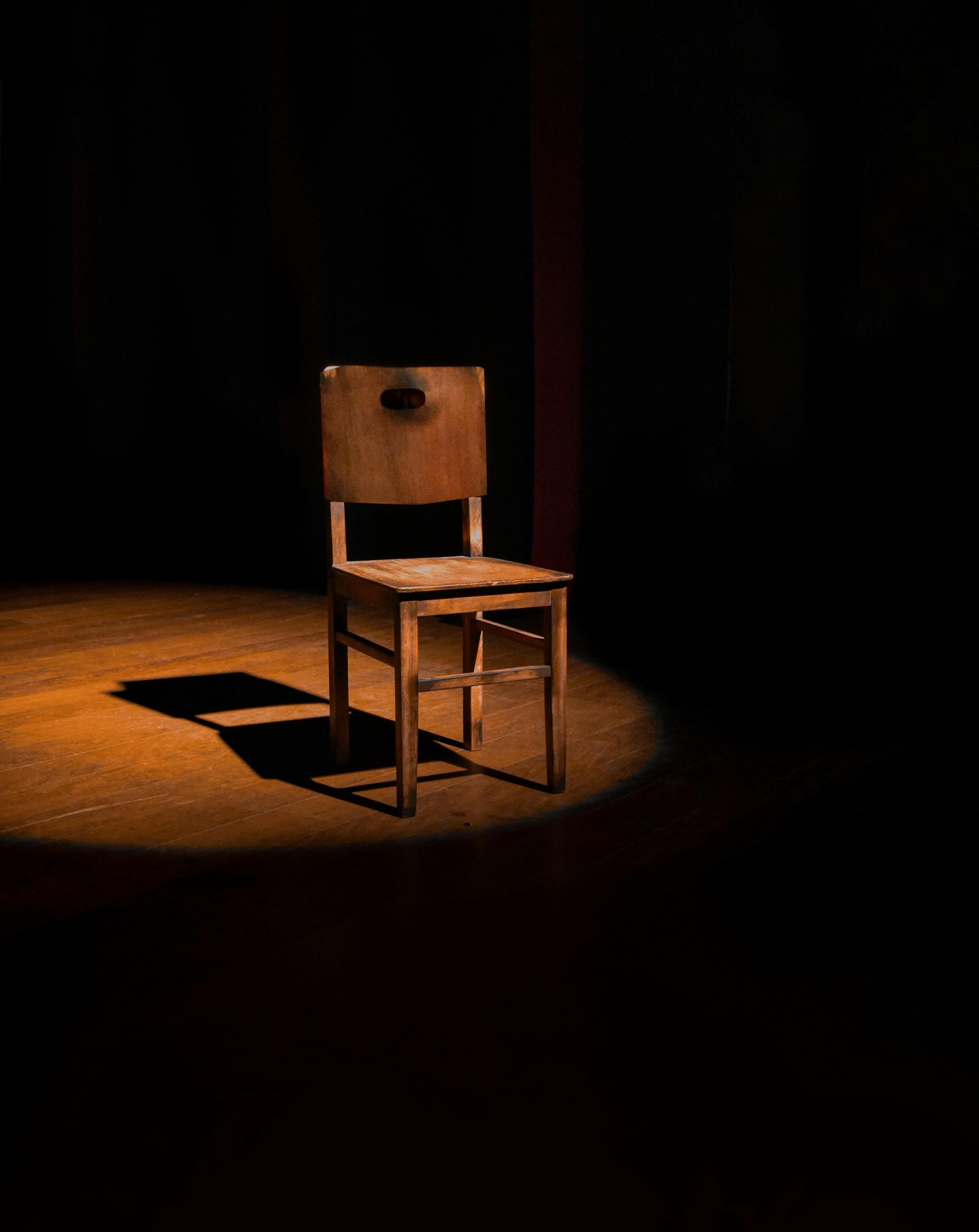 Une chaise éclairée sur une scène de théâtre.