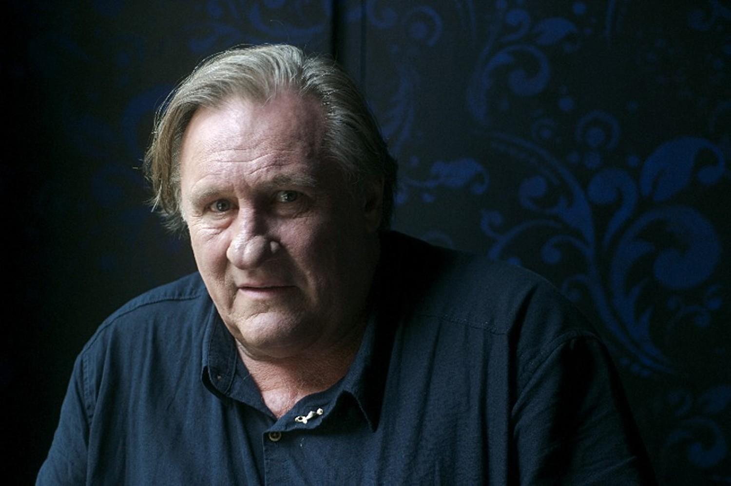 Gérard Depardieu pose sur un fond bleu marine.