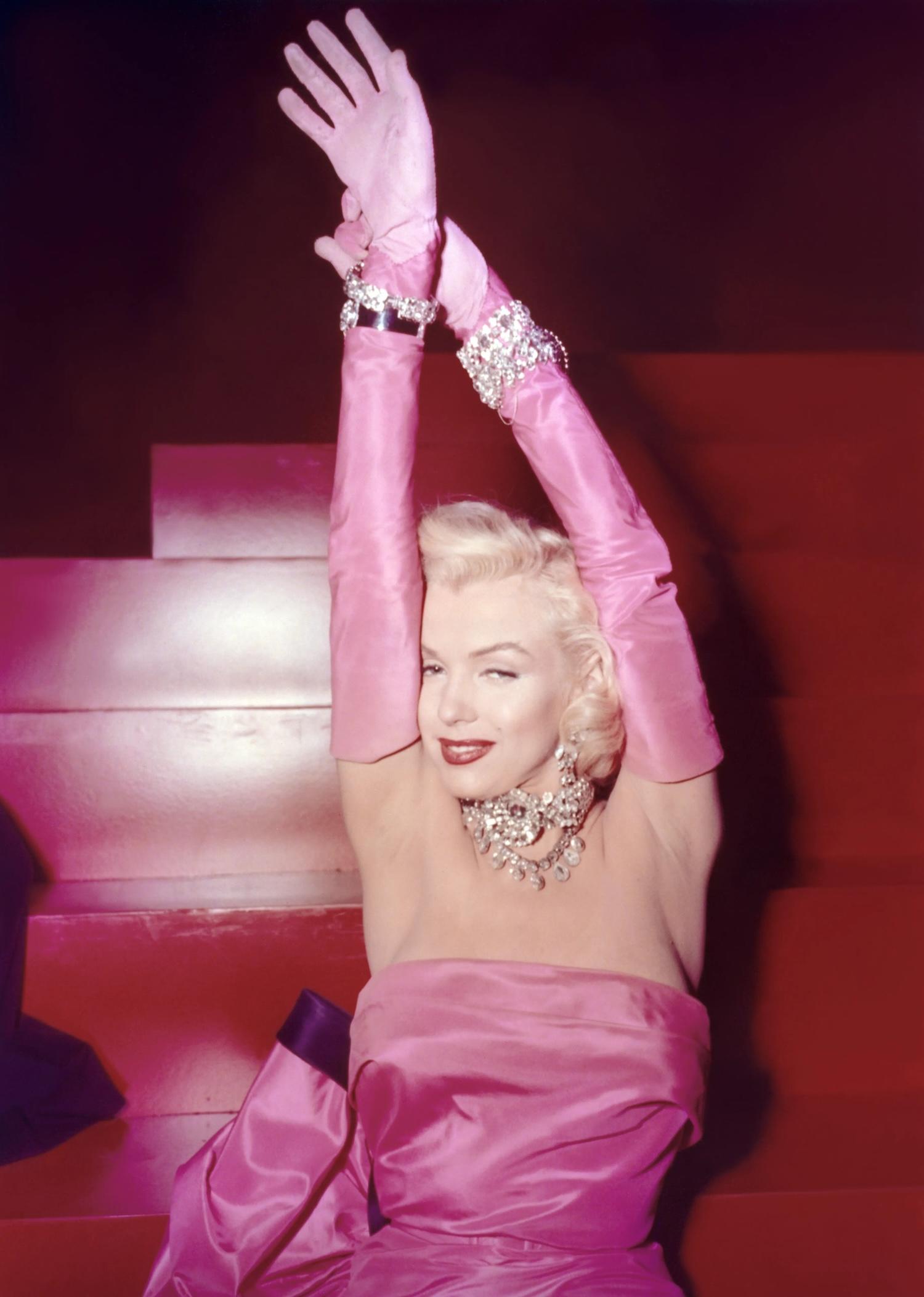 Marilyn Monroe portant une robe et des gants roses. 
