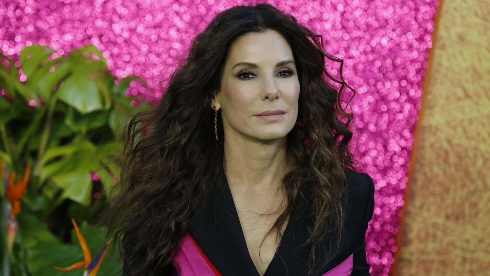 Sandra Bullock sur un fond rose pailleté. 