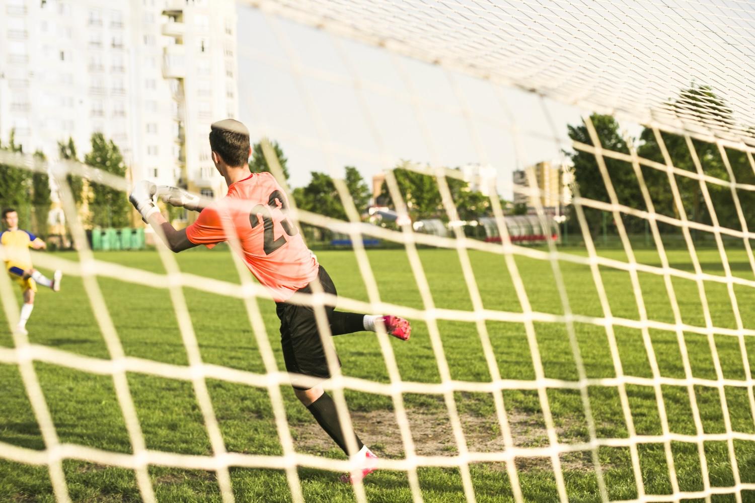 Un gardien de foot est en train d'arrêter un ballon dans un but.