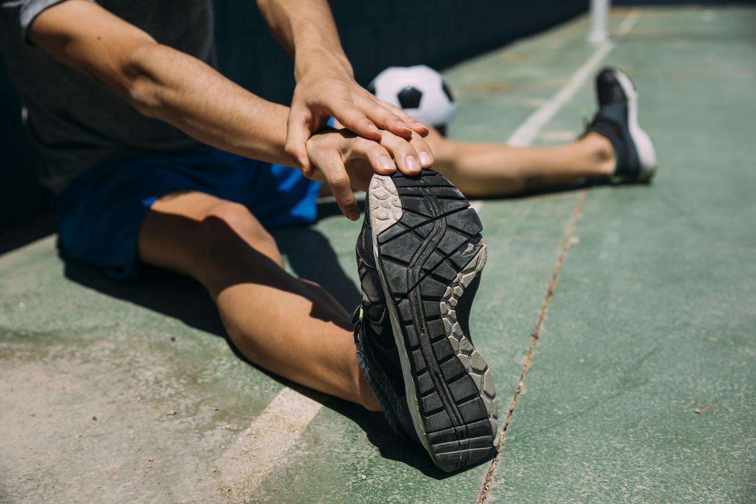 Un joueur de foot s'étire la jambe avant de jouer.