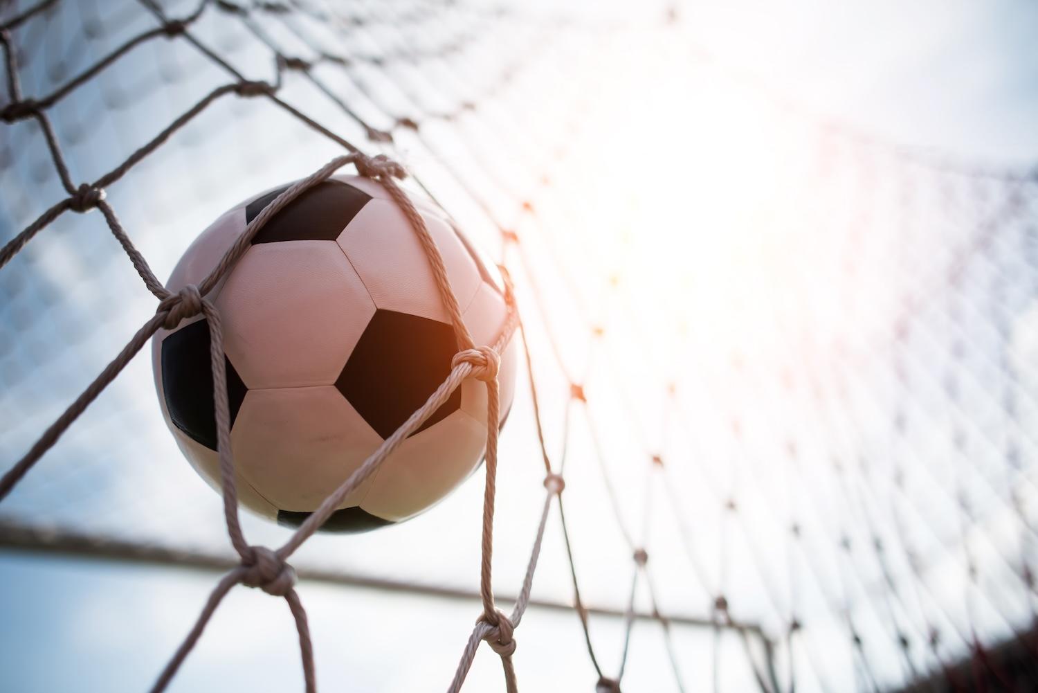 Un ballon de foot dans les filets d'un but.