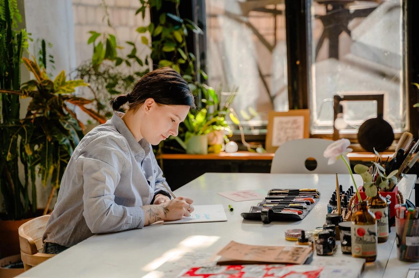 Une artistes dessine sur un bureau.