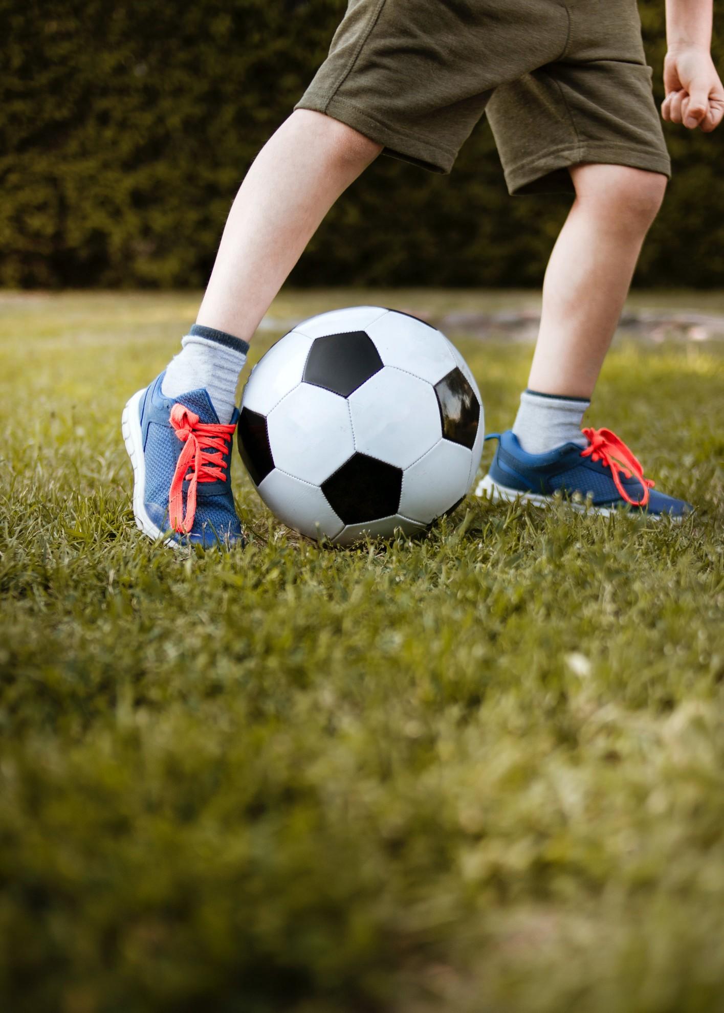Un enfant en train de pousser un ballon de football.
