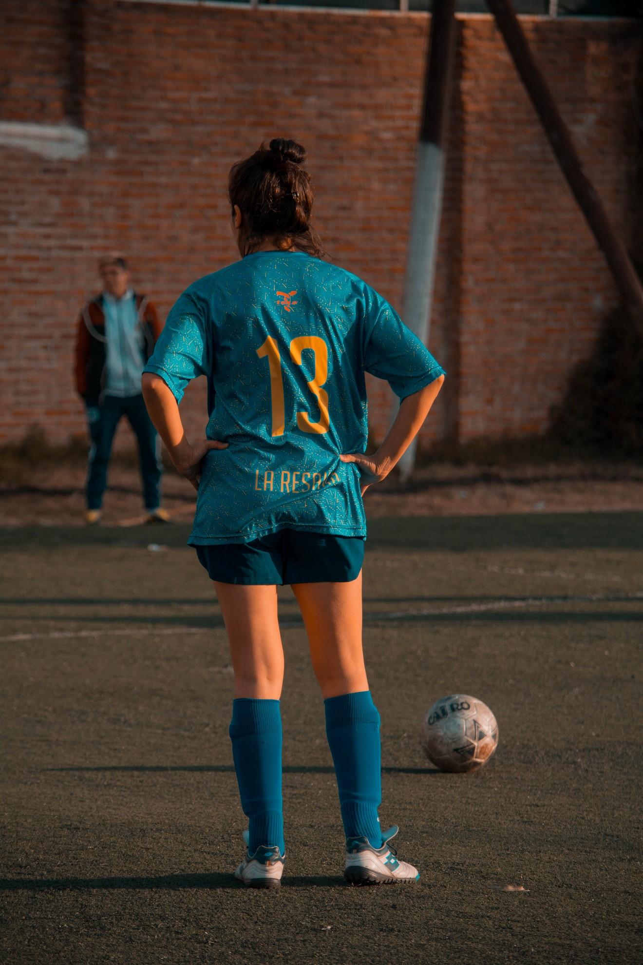 Une femme en plein match de foot.