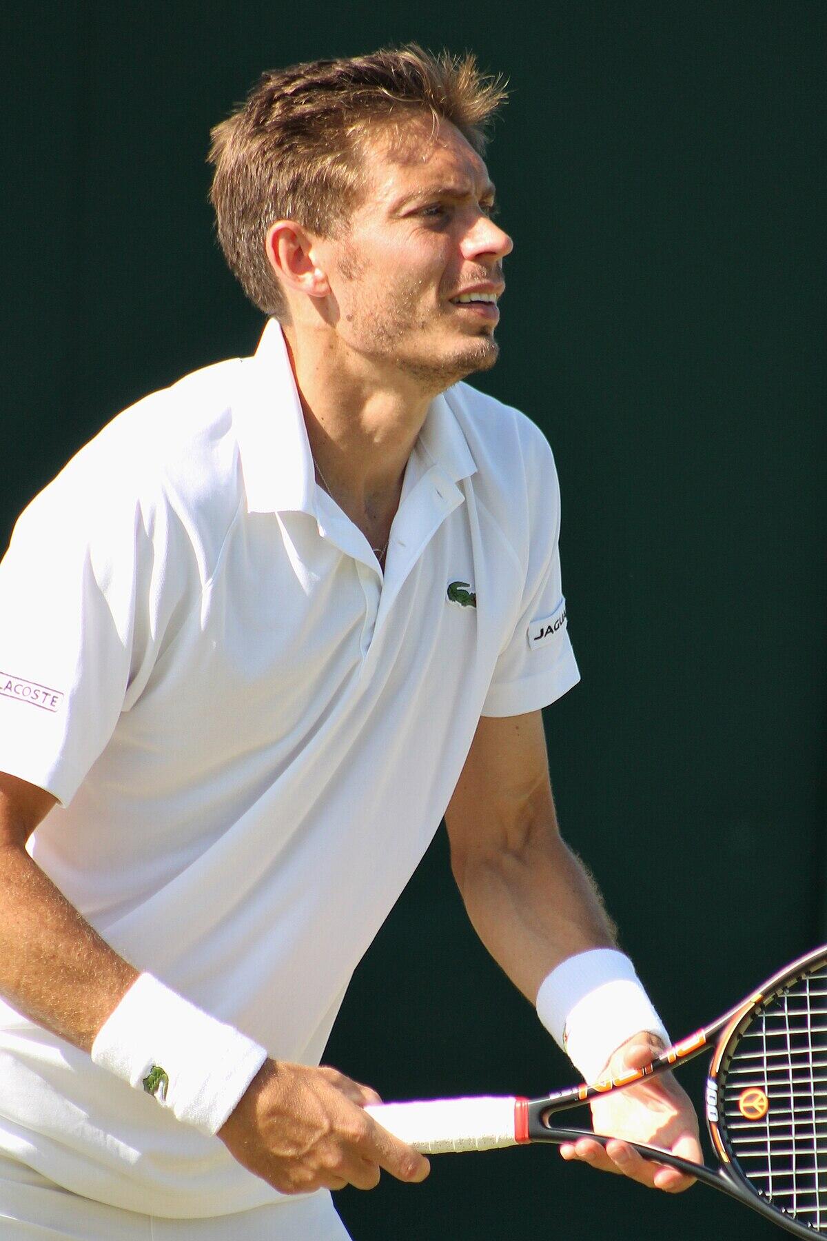 Photo de Nicolas Mahut sur un court de tennis, raquette à la main. 