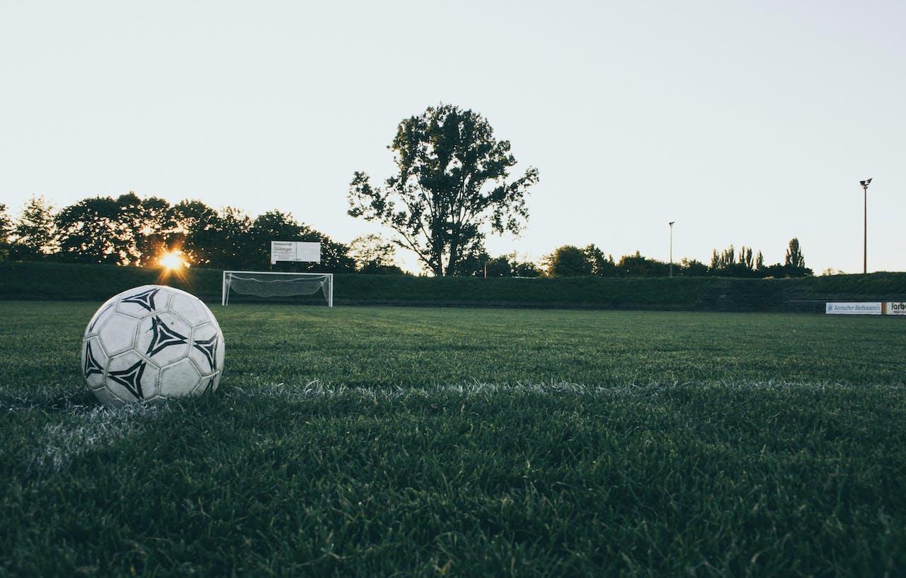 Ballon de foot posé sur une pelouse de stade.