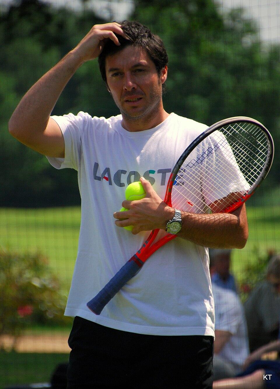 Photo de Sébastien Grosjean, raquette et balles de tennis à la main. 