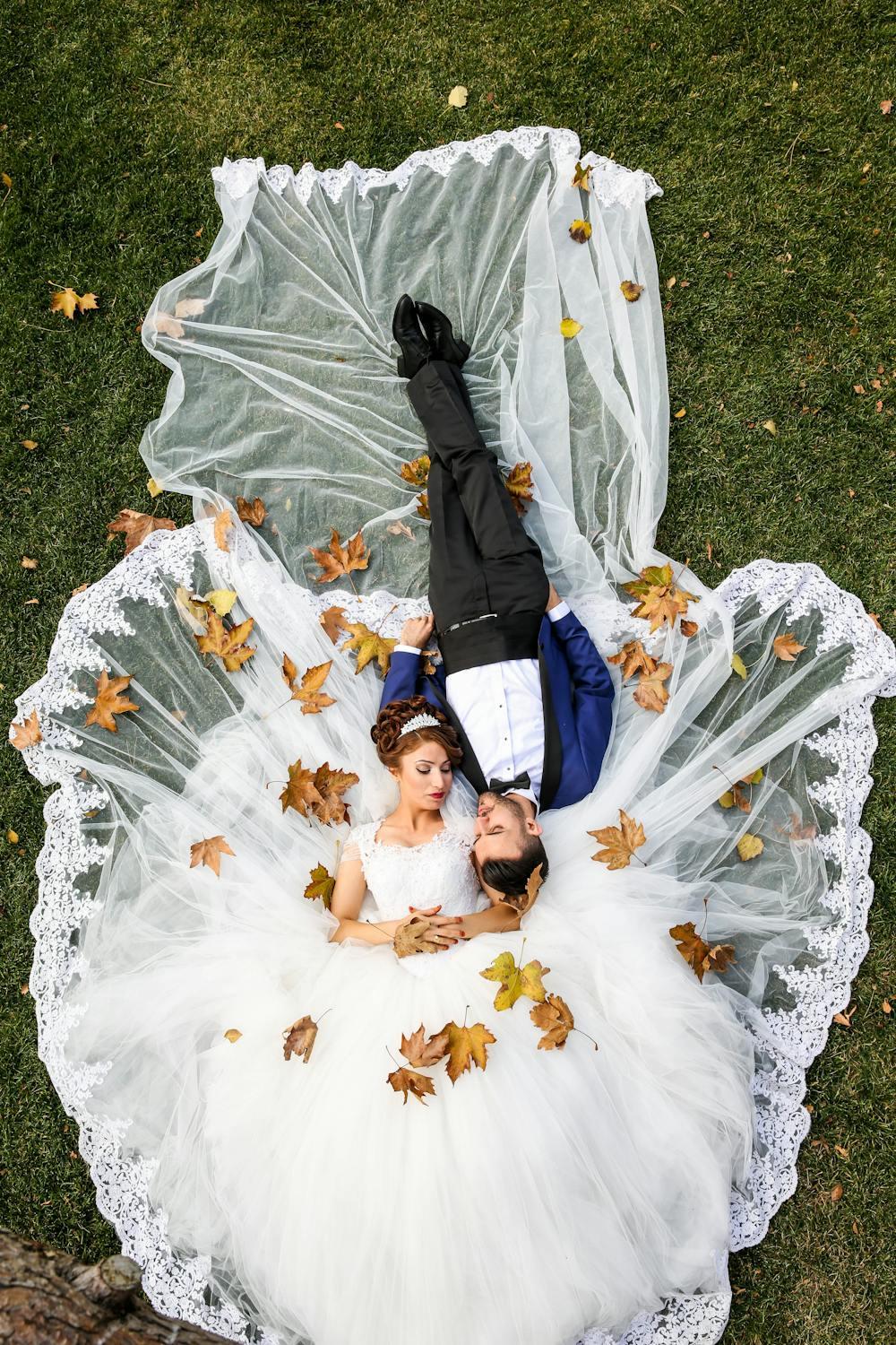 Un couple de mariés est allongé dans l'herbe.
