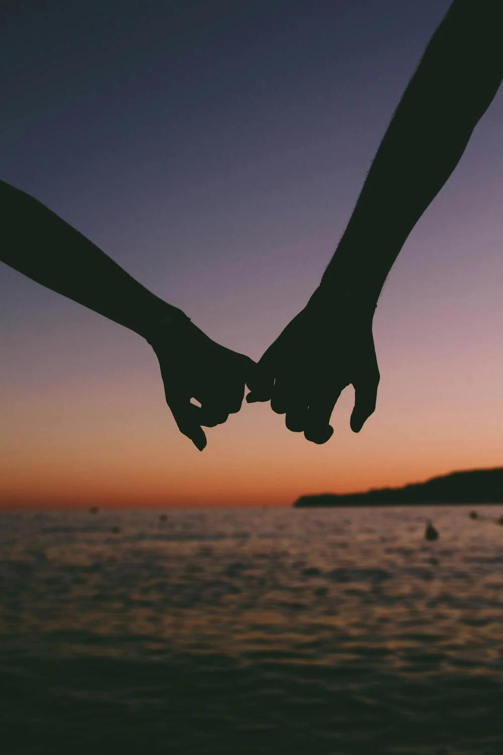 Un couple se donne la main au coucher du soleil.