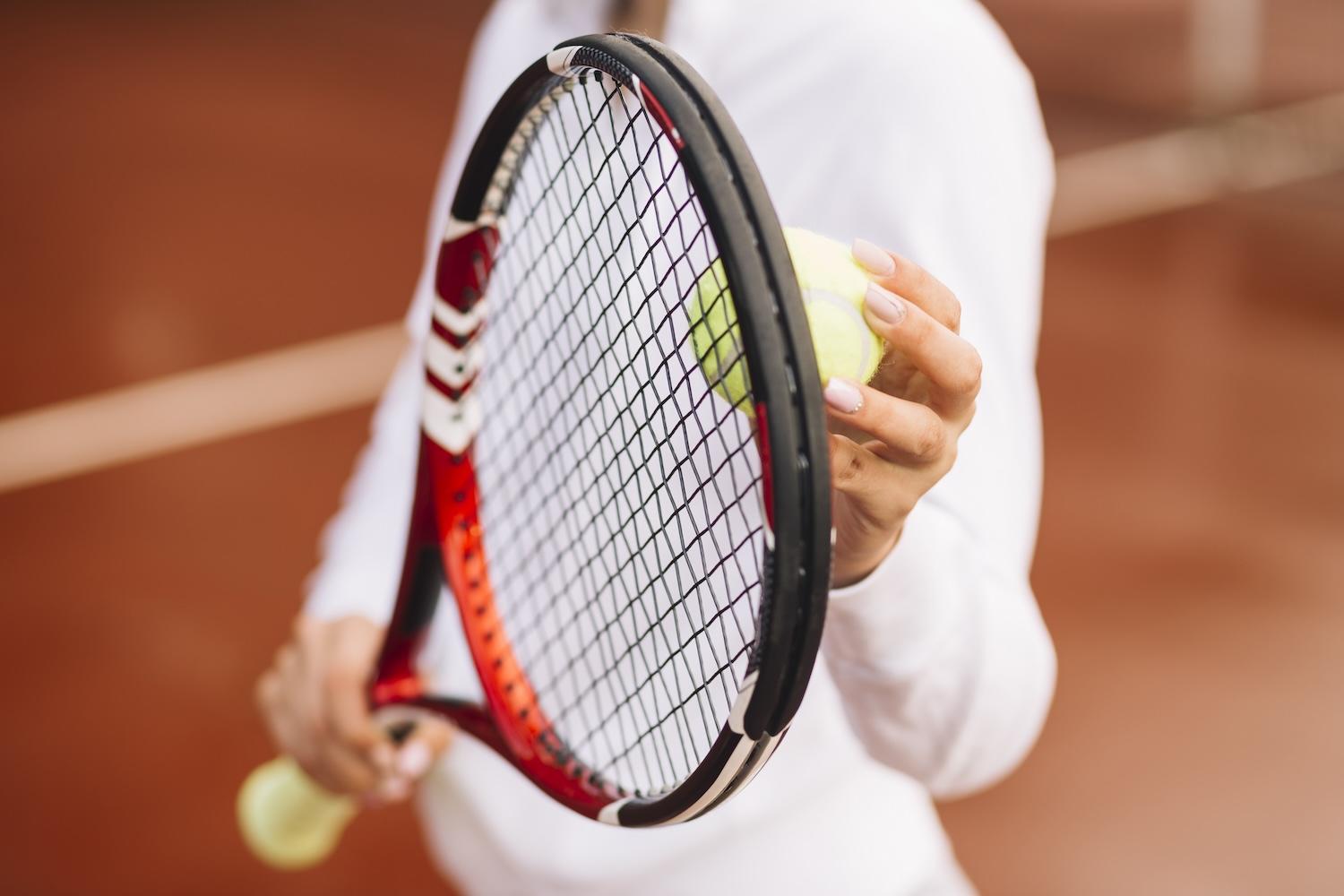 Une femme tient une raquette de tennis dans la main avec une balle.