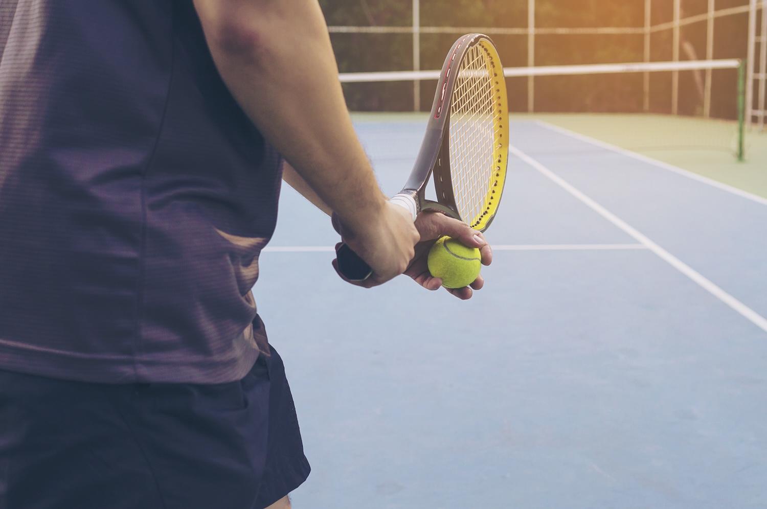 Un joueur de tennis se prépare à servir sur le court.