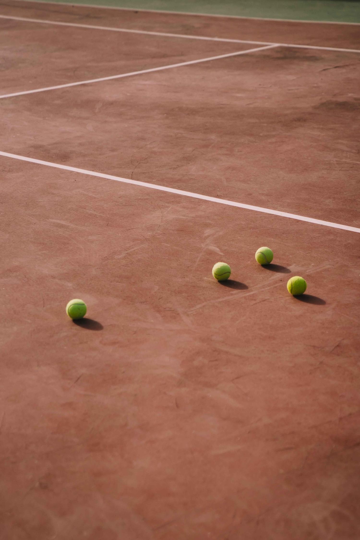 Plusieurs balles sont disposées sur un court de tennis.