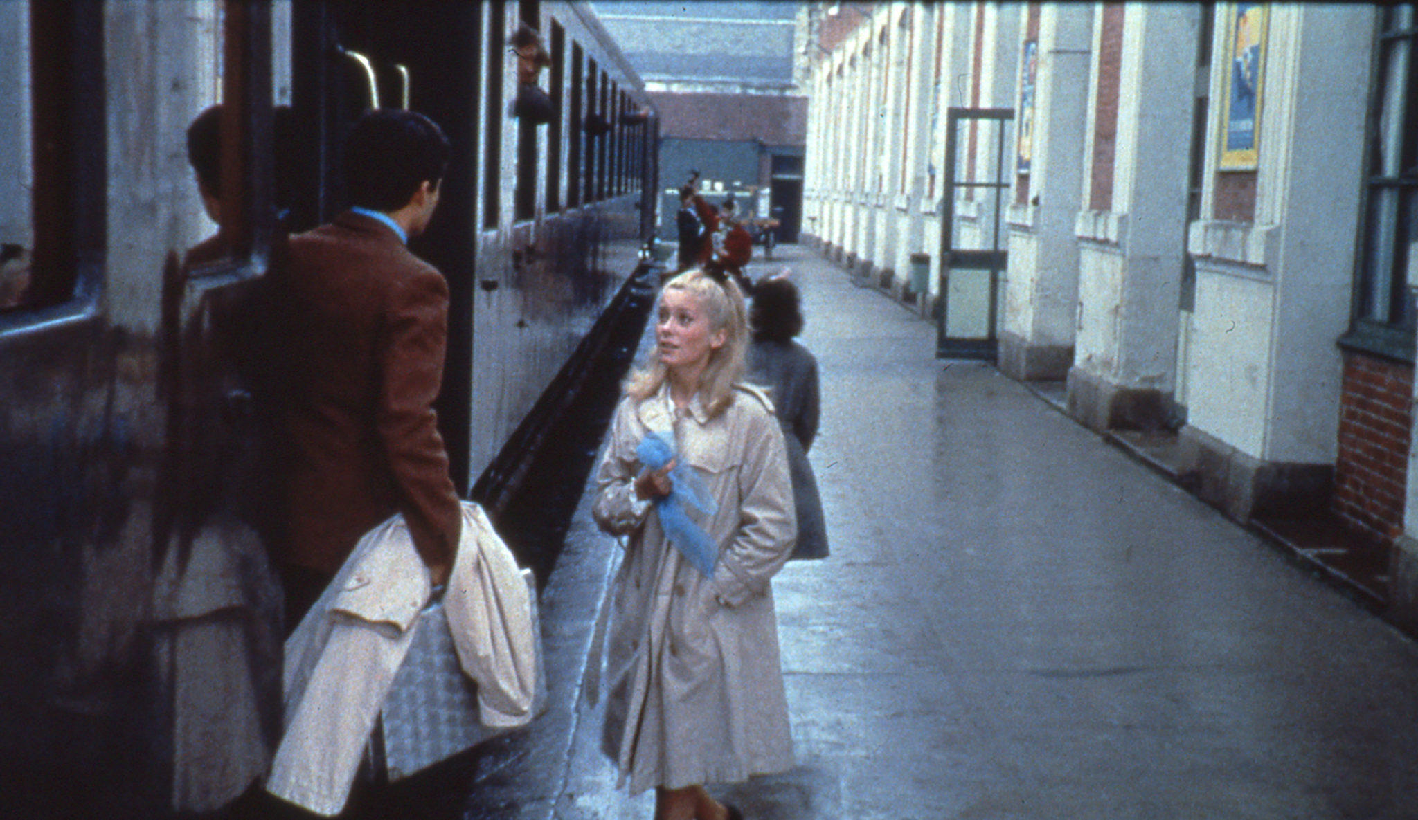 Une jeune femme est sur le quai de la gare et parle avec un jeune homme dans un train.