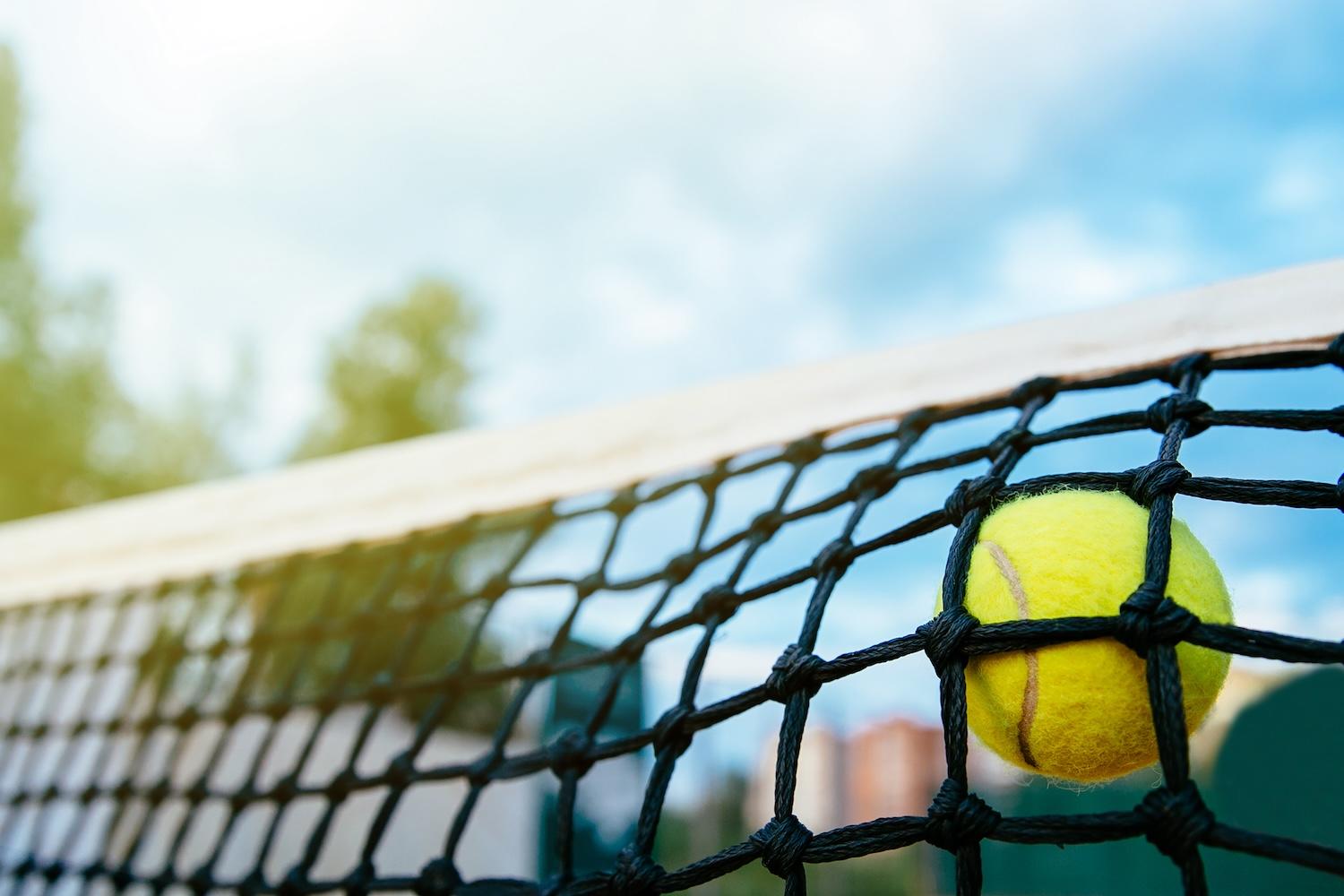 Une balle de tennis est prise dans un filet de tennis.