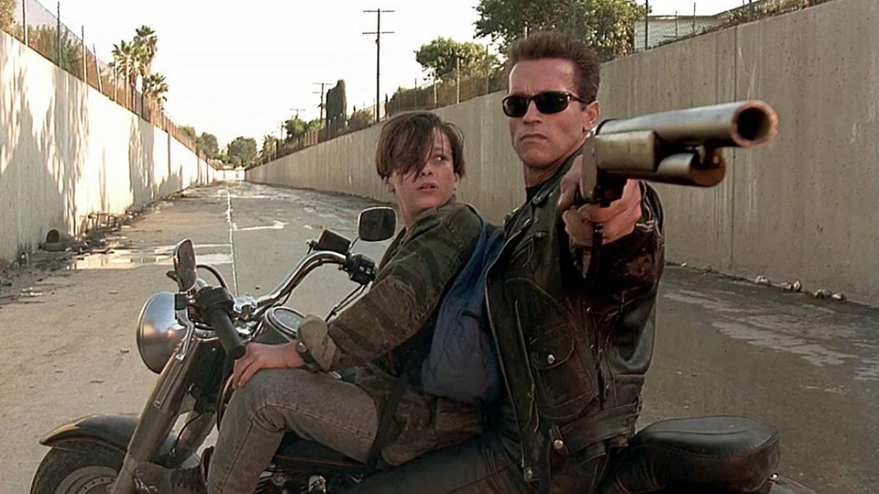 Deux hommes sur une moto avec un qui tient un fusil