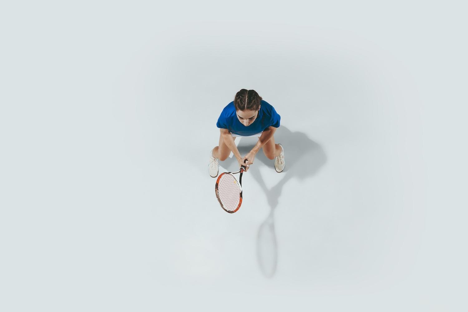 Une jeune femme vue du haut est en train de jouer au tennis.