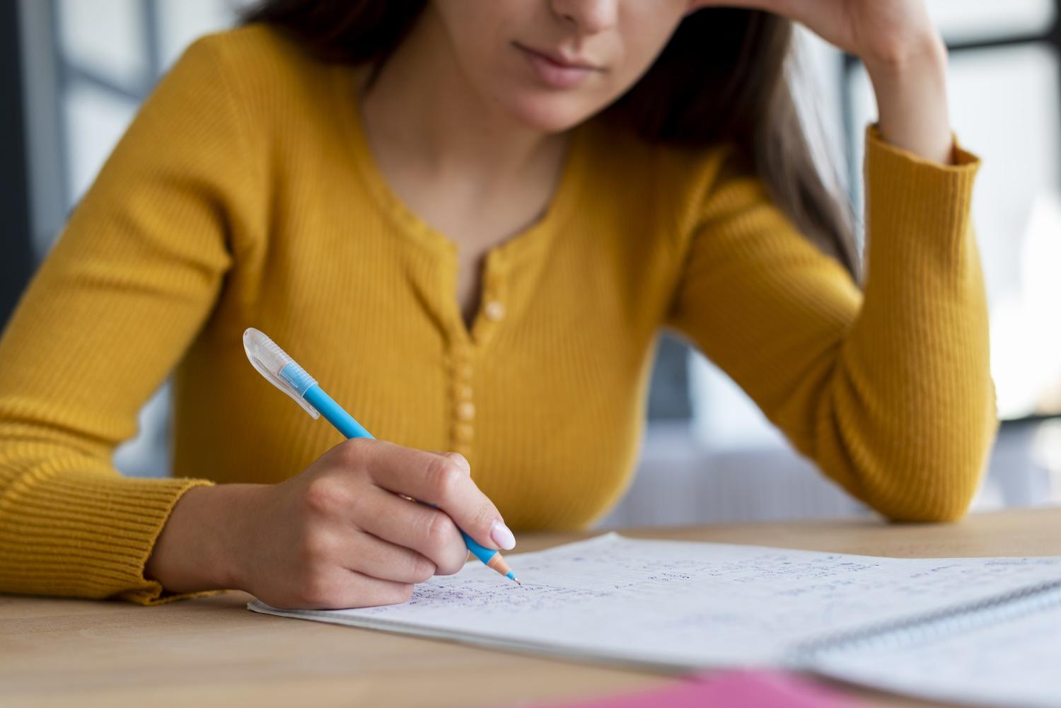 Une jeune femme est en train d'écrire sur une feuille.