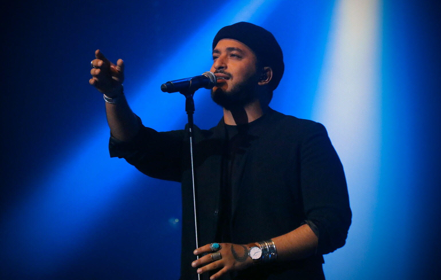 Le chanteur Slimane est en train de chanter avec un micro à pied.