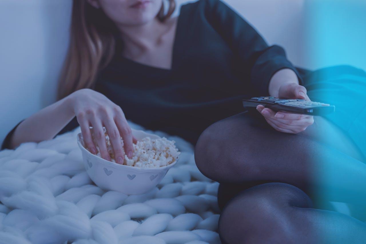 Jeune femme en train de regarder l'Eurovision en mangeant des pop corns.