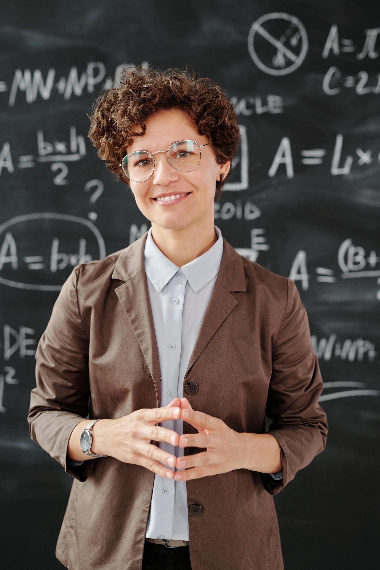 Une jeune prof de maths devant un tableau noir.