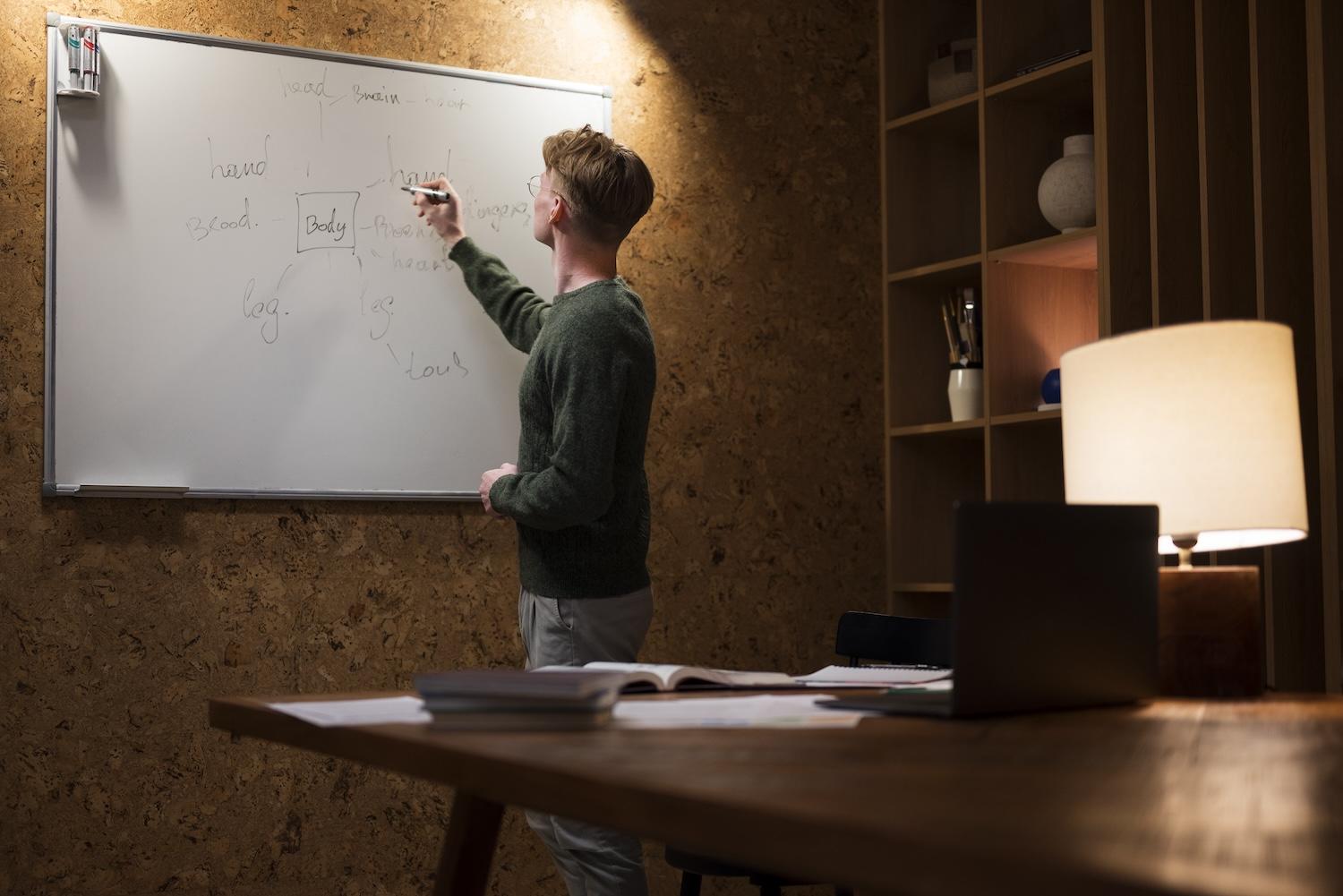 Un jeune homme fait une présentation sur un tableau blanc.