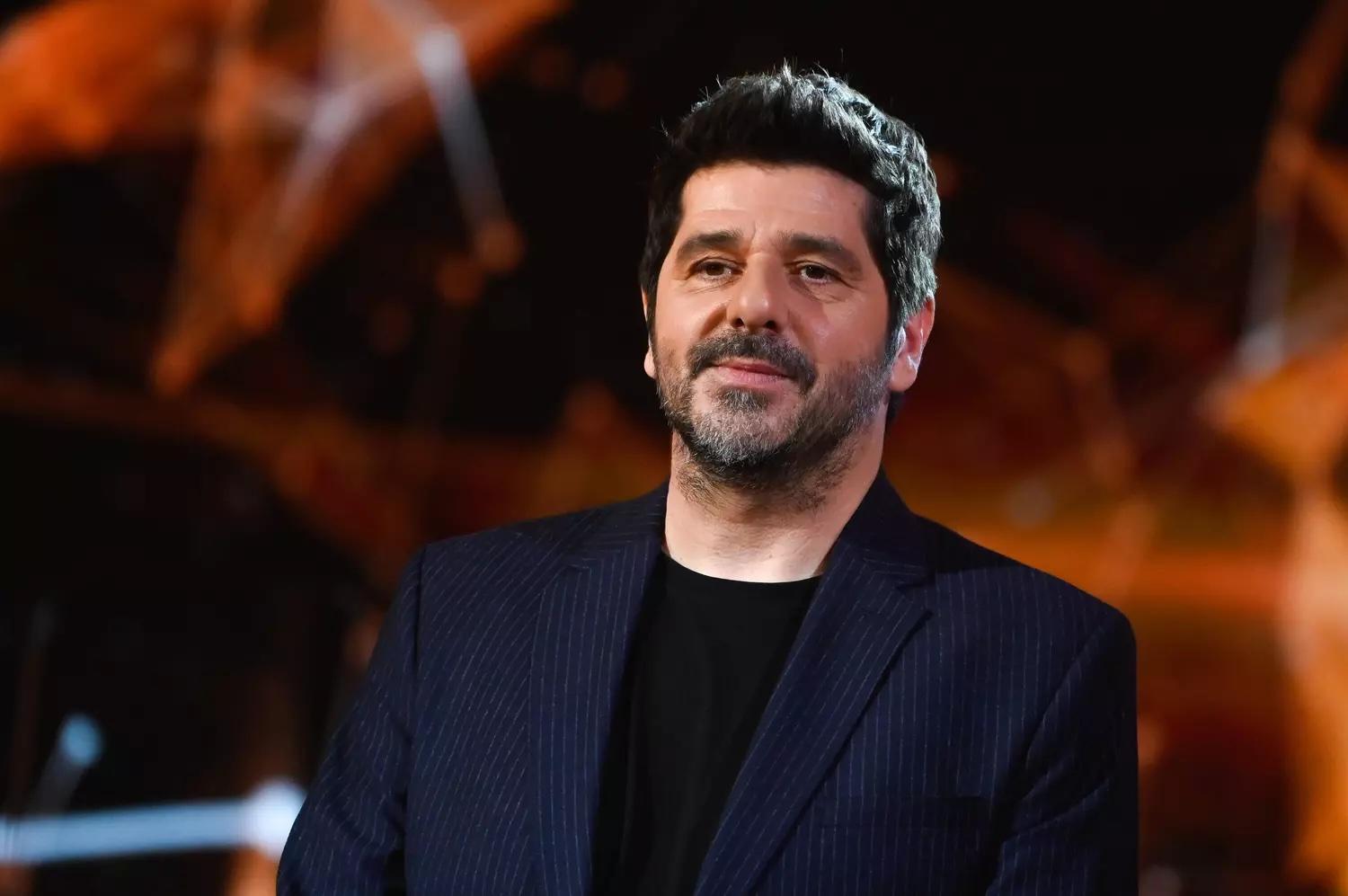 Le chanteur Patrick Fiori sur une scène en costume noir.