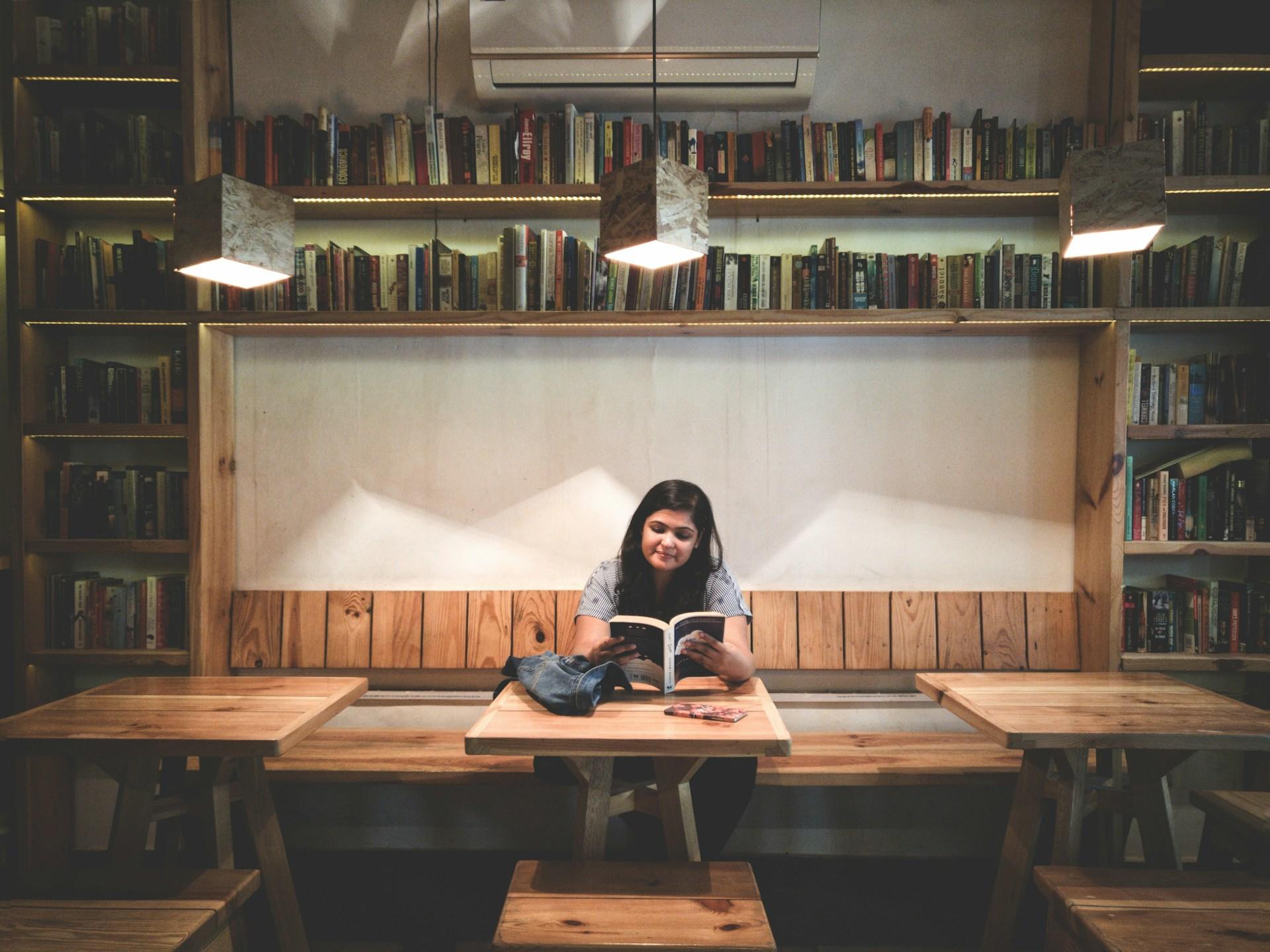 personne assise à un bureau entourée de livres