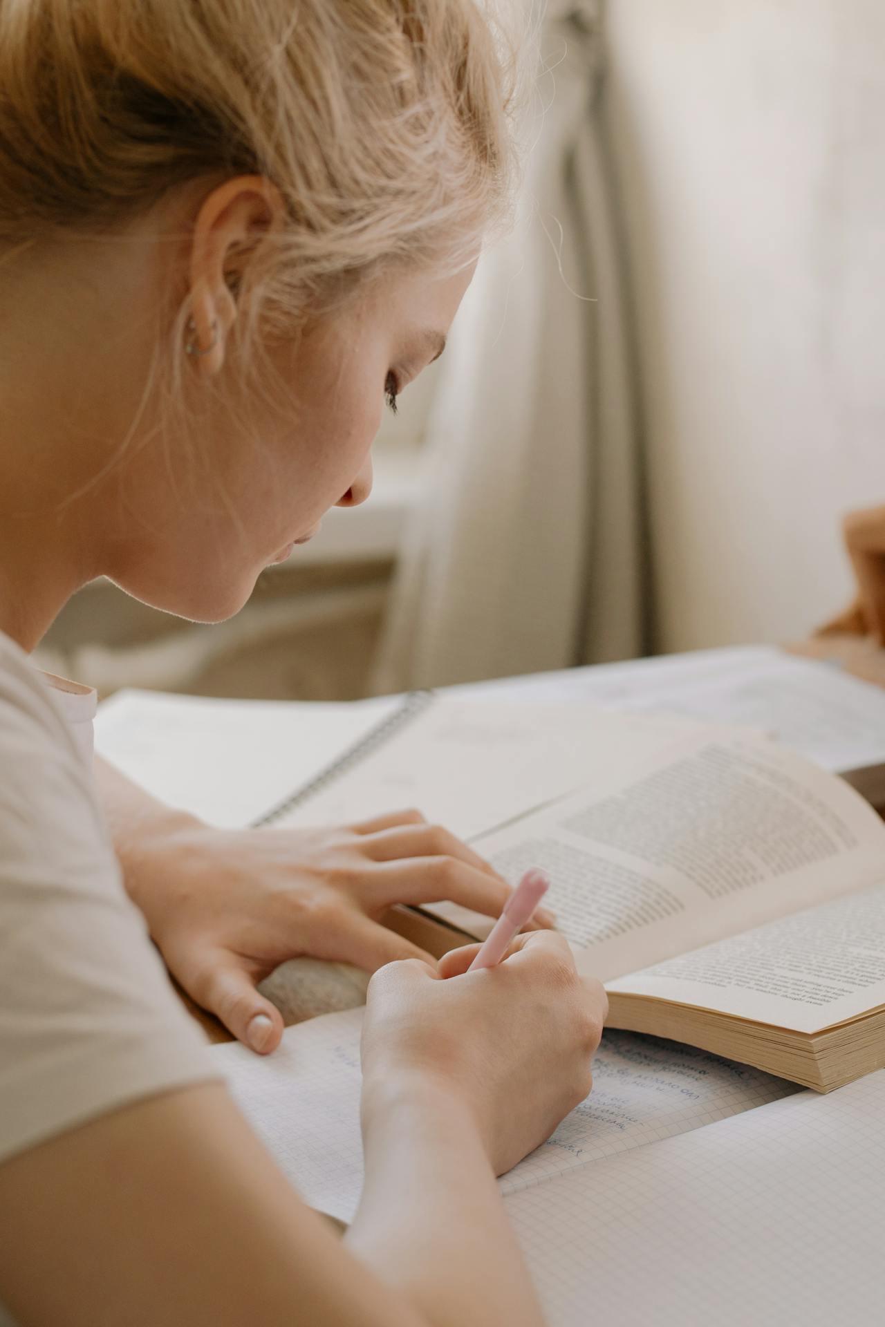 Jeune femme blonde en train d'écrire sur un carnet pour préparer le CAPES. 