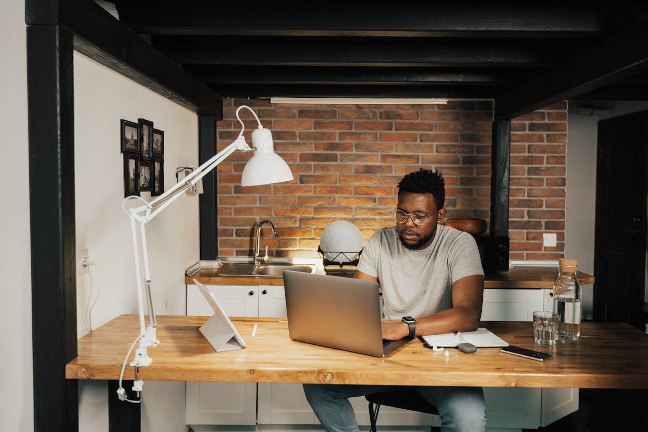 Jeune homme noir à son bureau, derrière son ordinateur, en train de candidater pour un master.