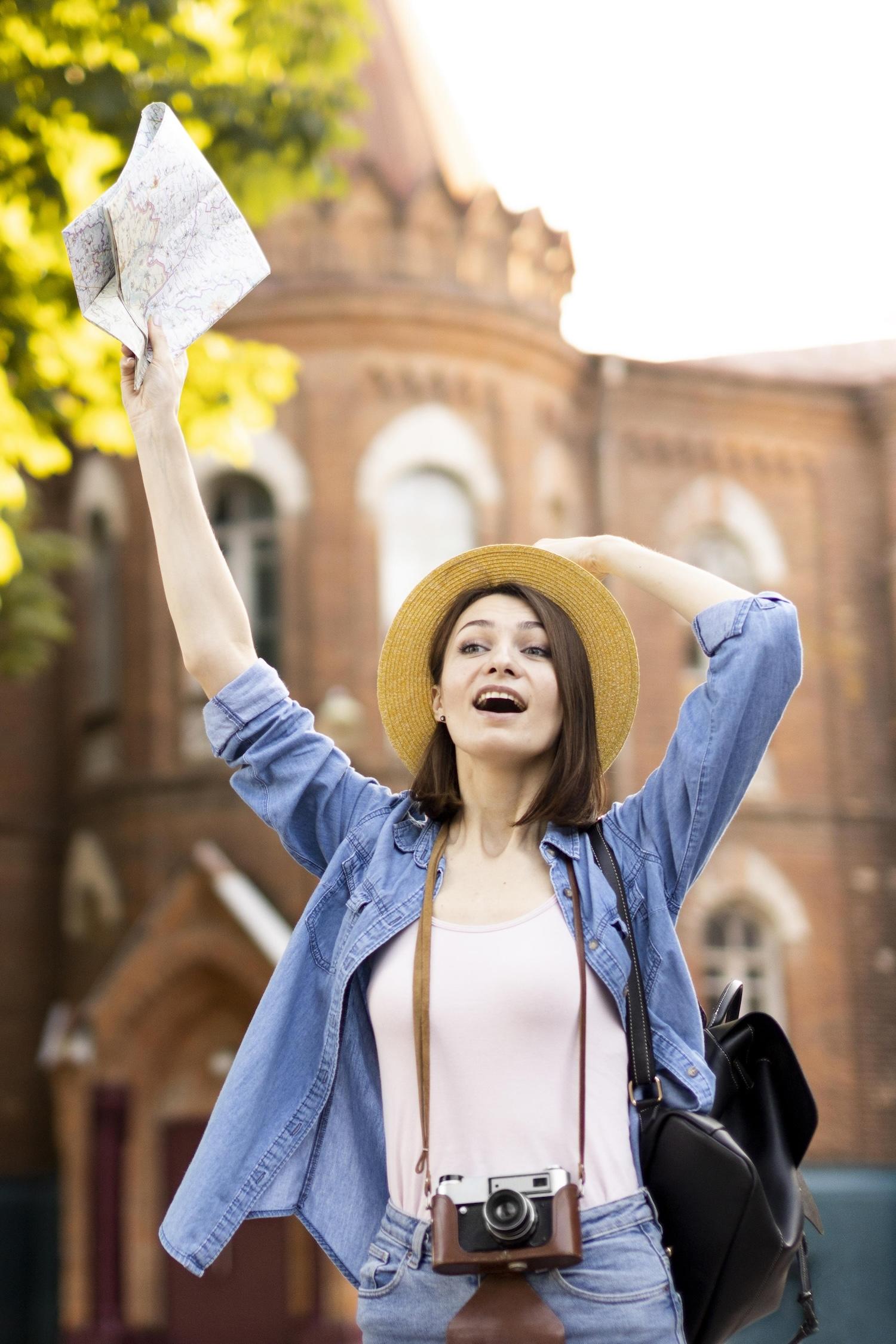 Une jeune femme tient une carte à la main et a un appareil photo autour du cou.
