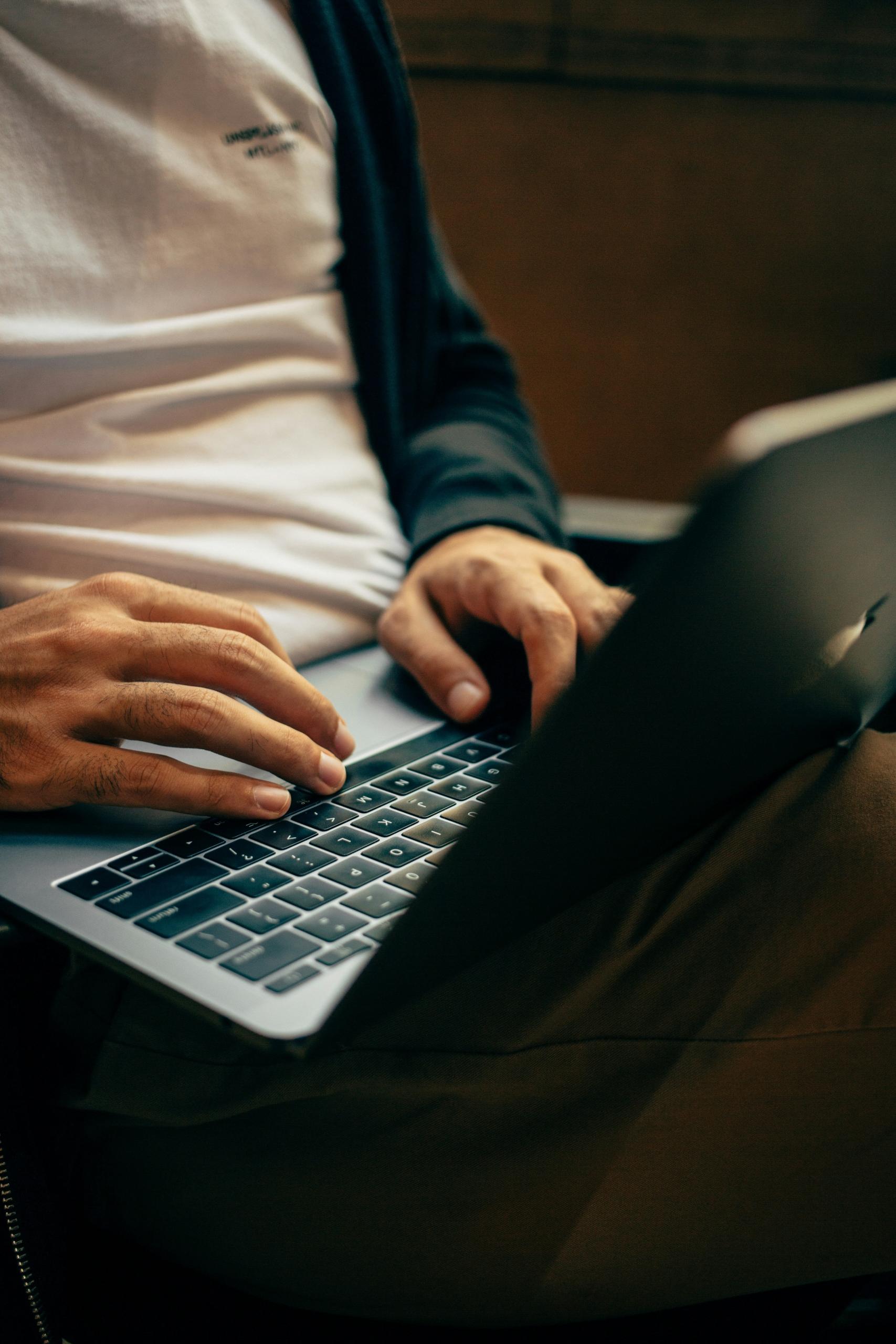Des mains tapent sur un clavier d'ordinateur portable.