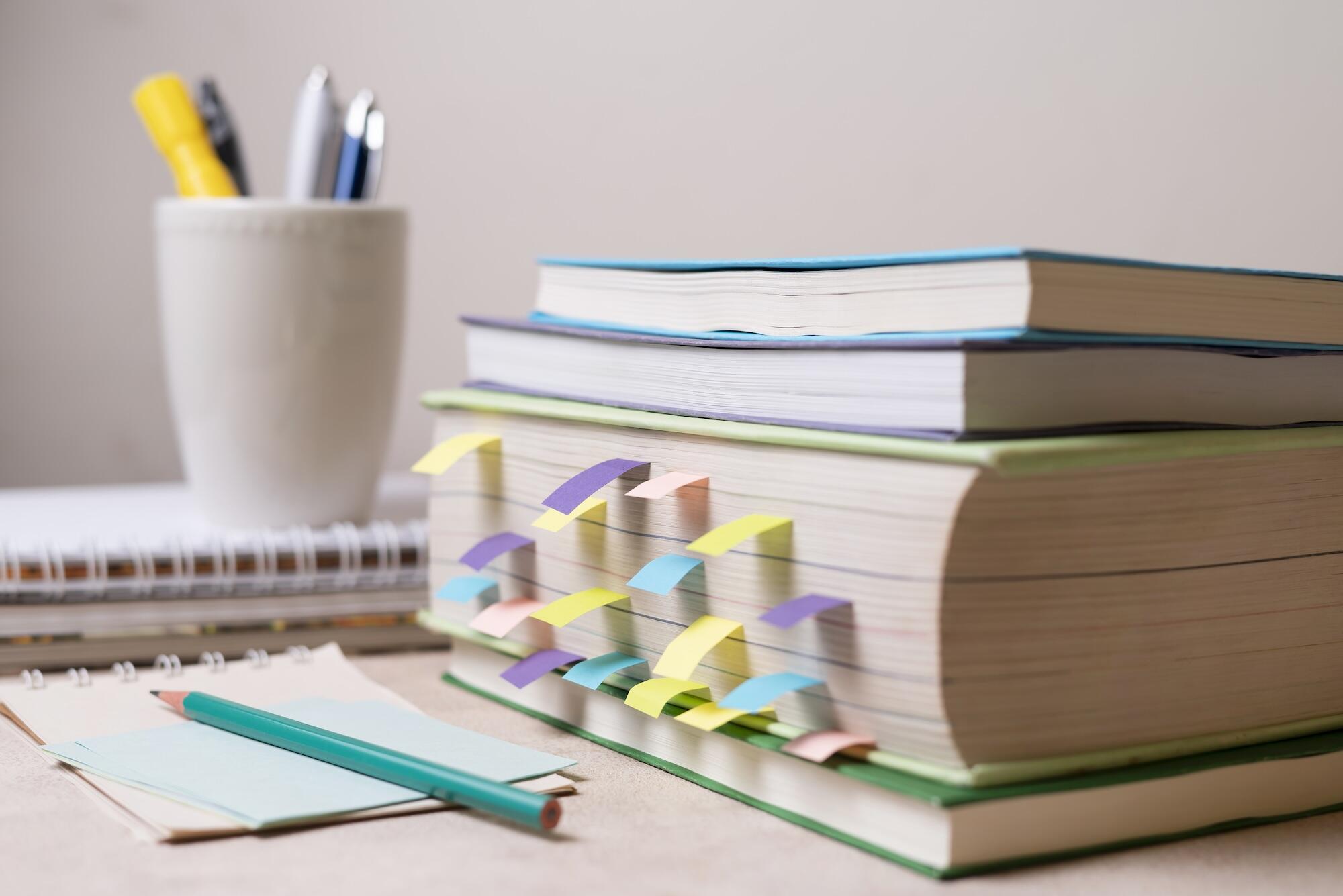 Un livre de cours avec des post-it posé sur une table