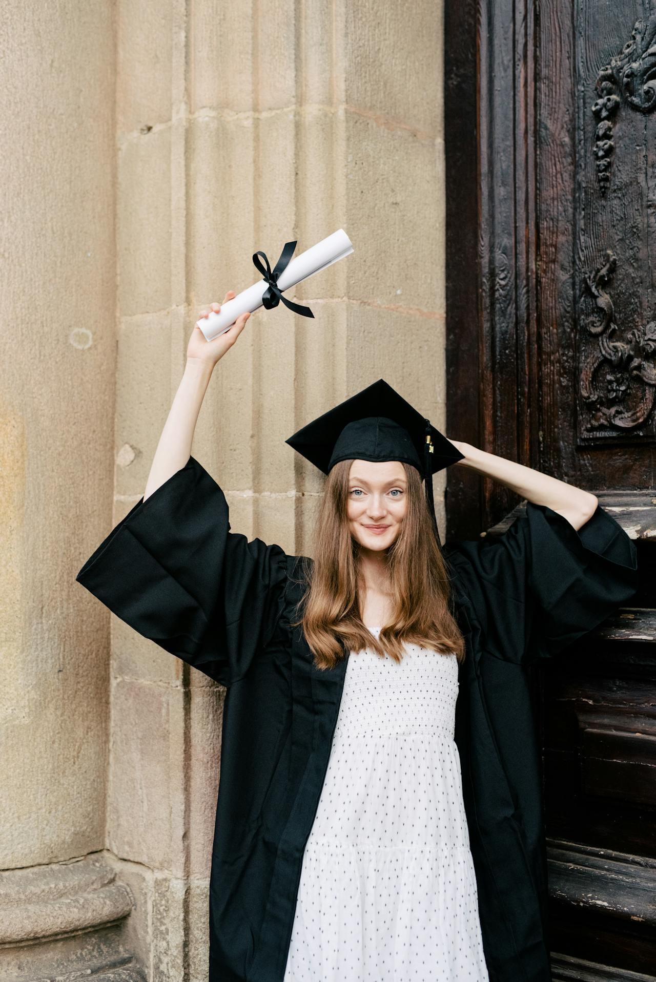 Jeune femme brandissant un diplôme au-dessus de sa tête.