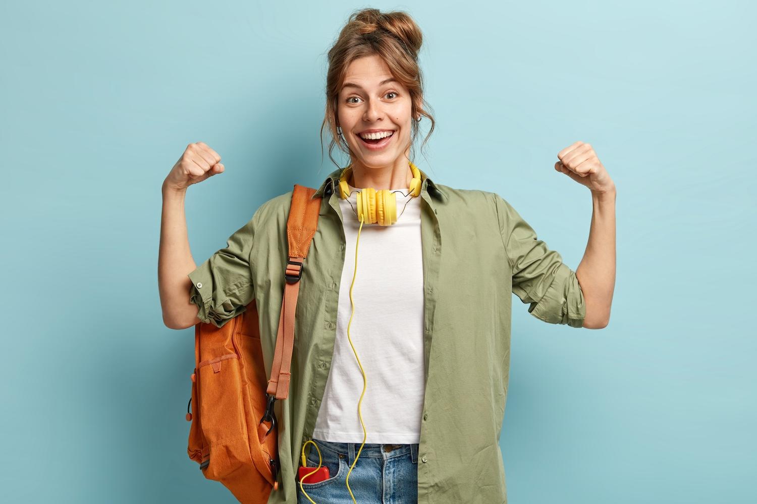 Une jeune femme avec un sac à dos et un casque autour du cou. 