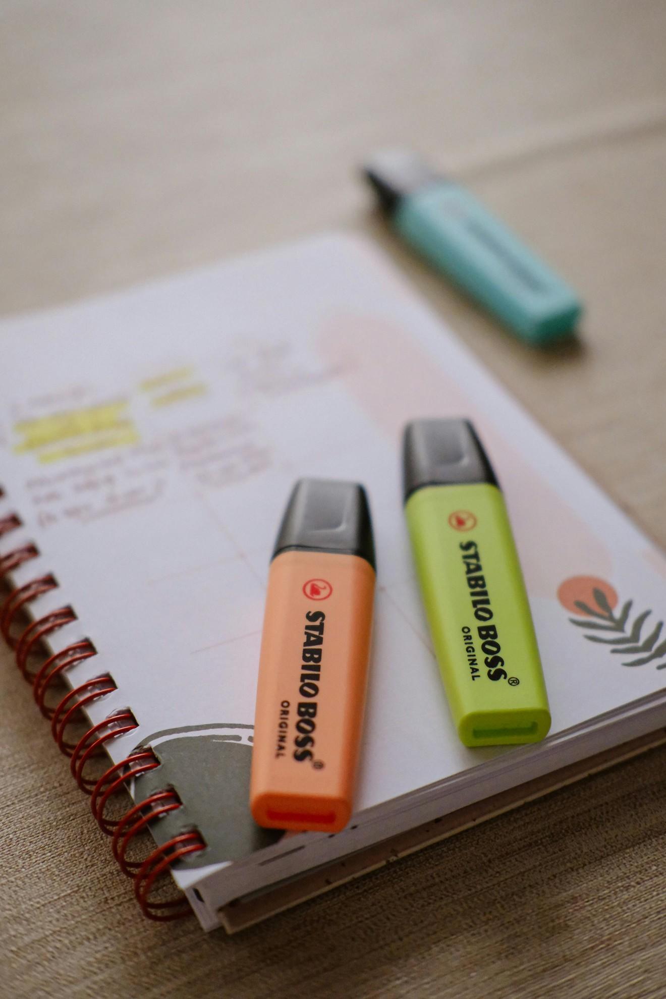 Un cahier et des surligneurs pour étudier.