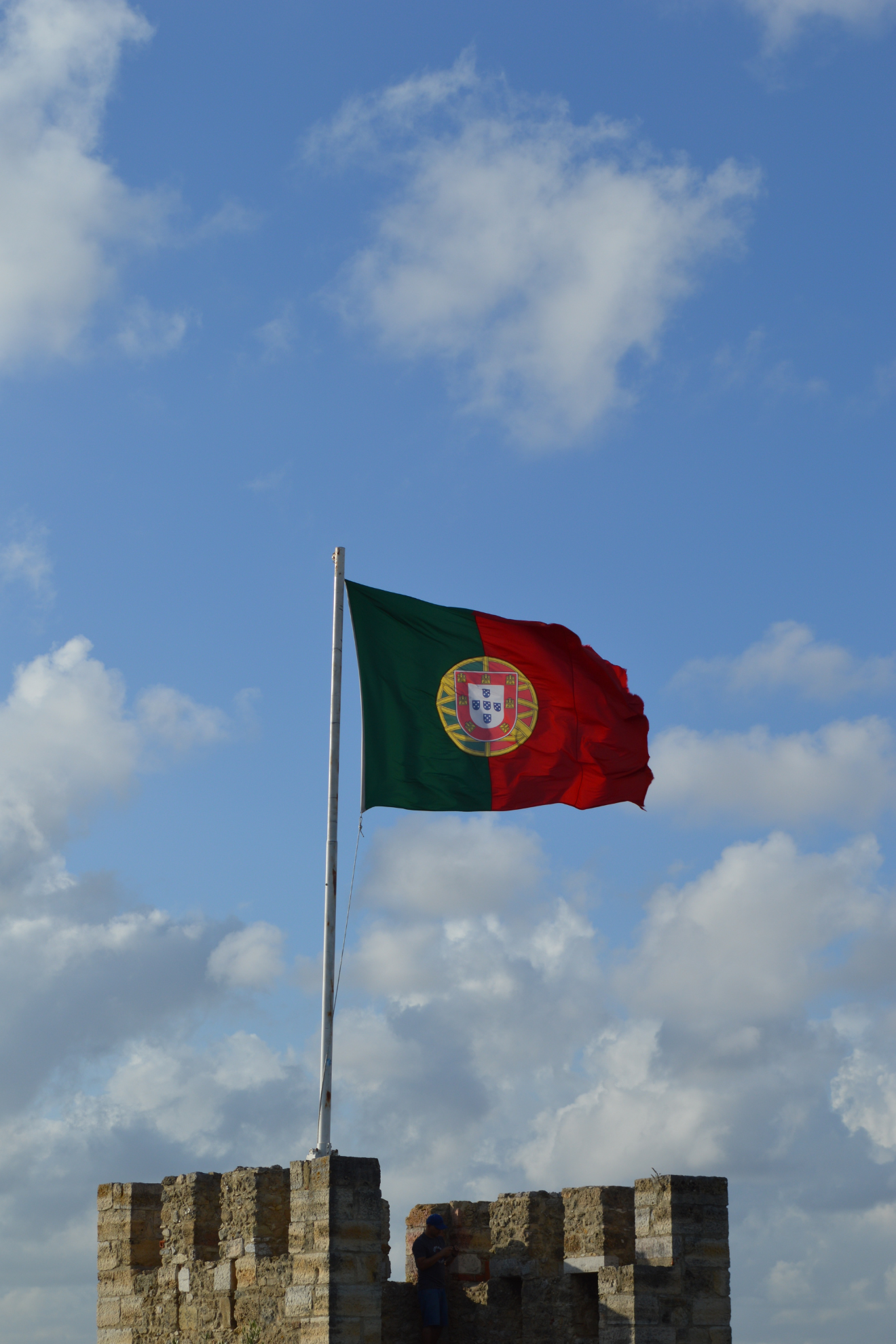 Le drapeau portugais planté sur une tour crénelée.