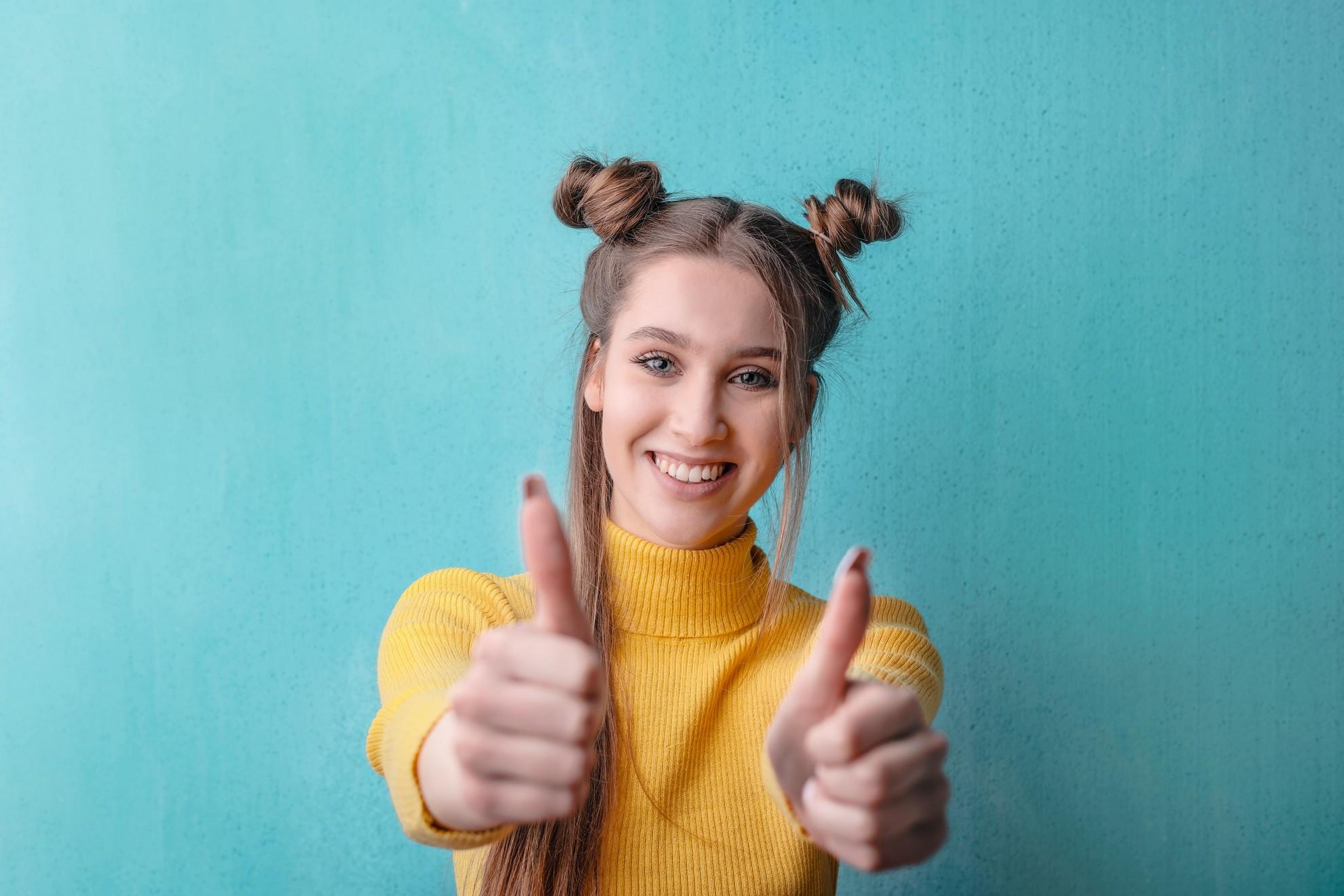 Une jeune femme heureuse, les pouces levés.